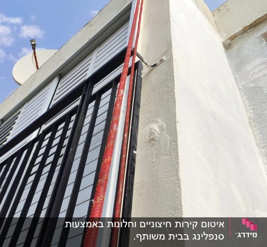 צינור אדום מחובר לקיר לבן עם איטום